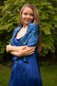 Side view of model wearing long reversible silk satin scarf in blue floral print and cobalt.