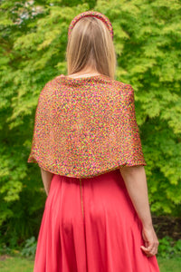 Back view of Model wearing reversible orange/pink dotted print silk satin shawl with pearl fastener at the chest, with matching padded headband and raspberry pink Victoria Gown.