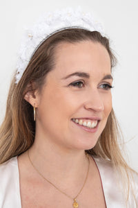 a white padded headband with stunning intricate detail in the lace trim and pearls handmade in London