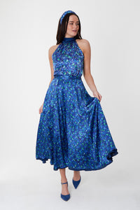 Model wearing reversible voluminous a-line midi silk satin blue floral print skirt, worn with matching halter neck Sophie Top and padded headband.