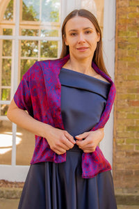 a mixed red, pink and burgundy printed silk satin scarf worn over a gown