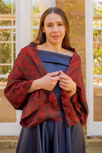 a red and black printed silk satin scarf worn over a gown