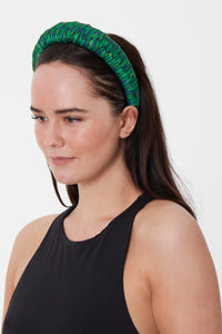 An emerald green printed silk satin headband worn by a model that is handmade sustainably