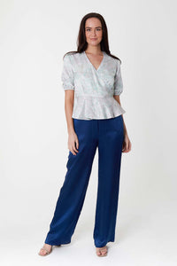 Model wearing high waisted narrow fit silk viscose palazzo pants in textured navy, worn with pale pastel floral wrap Judy Top.