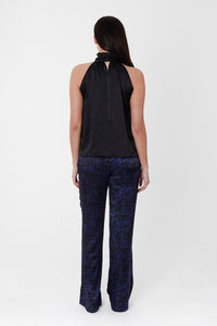 Back view of model wearing an Isabel Manns high waisted narrow fit palazzo pants in black camo silk satin print, worn with matching headband and black halter neck Sophie Top.