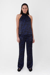 Model wearing an Isabel Manns high waisted narrow fit palazzo pants in black camo silk satin print, worn with matching halter neck Sophie Top and headband.