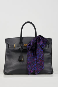 a purple printed silk satin scarf tied in a bow on a bag