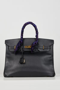 a purple printed scarf tied on a handle of a bag