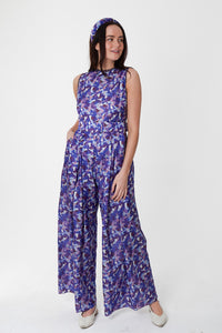 A front view of a sleeveless wide leg silk bamboo jumpsuit and matching belt that comes in a vibrant purple print.