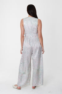 A back view of sleeveless wide leg silk cotton jumpsuit and matching belt that comes in a pastel blue print.