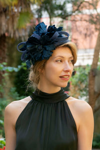 a detail shot of a black silk satin halter neck dress, worn with a fascinator