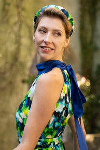 a detail shot of a colourful vibrant printed silk satin halter neck dress with cobalt collar and a matching tie belt