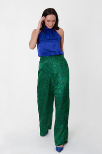 Model wearing an Isabel Manns reversible high waisted silk satin palazzo pants in vibrant green print, worn with matching halter neck Sophie Top in cobalt.