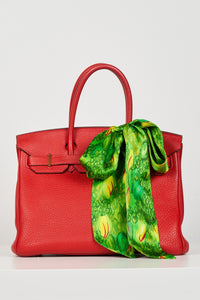 a green printed silk satin tie scarf accessorised as a bow on a birkin bag