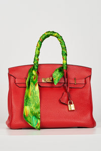 a green printed silk satin tie scarf accessorised on the handle of a birkin bag