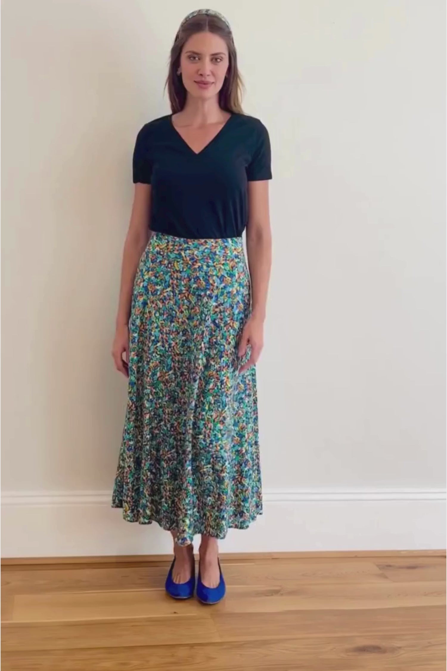 Video of model wearing a-line midi silk bamboo green multicoloured printed skirt, worn with black v-neck t-shirt.