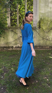 Video of an Isabel Manns princess seam wool crepe dress in teal. Features 3/4 length elasticated sleeves, a rounded elegant neckline, and belt with buckle.