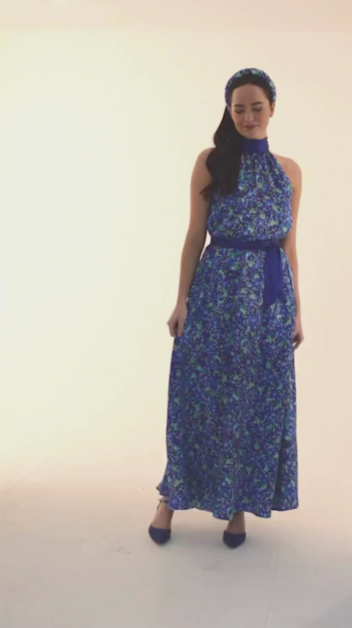 an elegant blue floral printed silk satin halter neck dress worn by a model showing the glamorous movement