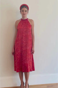 a video showing a women walking in a midi length halter neck silk satin dress in a vibrant red print