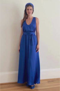 a cobalt blue long gown with a matching tie belt being worn by a model showing the front and back view as she walks towards the camera