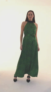 a green printed silk long halter neck dress worn by a model in a video showing the elegance and contrasting black neck tie