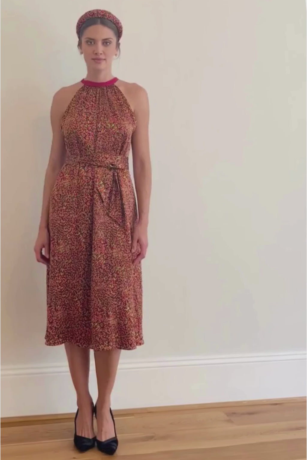 a video showing a women walking in a midi length halter neck silk satin dress in a vibrant print