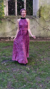 A video of a purple dotted printed silk satin long halter neck style dress with a black collar worn by a model and waist cinched in with a tie belt