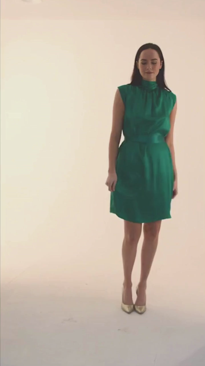 emerald green silk satin knee length halter neck dress with short sleeves video of model wearing it glamorously