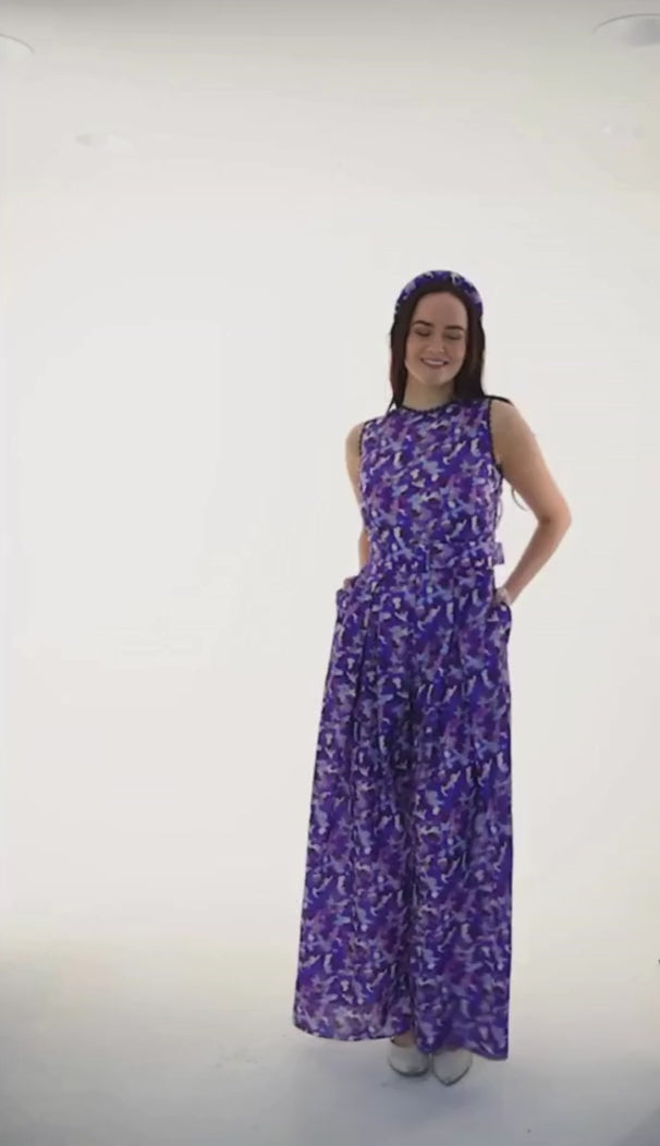 Video of sleeveless wide leg silk bamboo jumpsuit and matching belt that comes in a vibrant purple print.