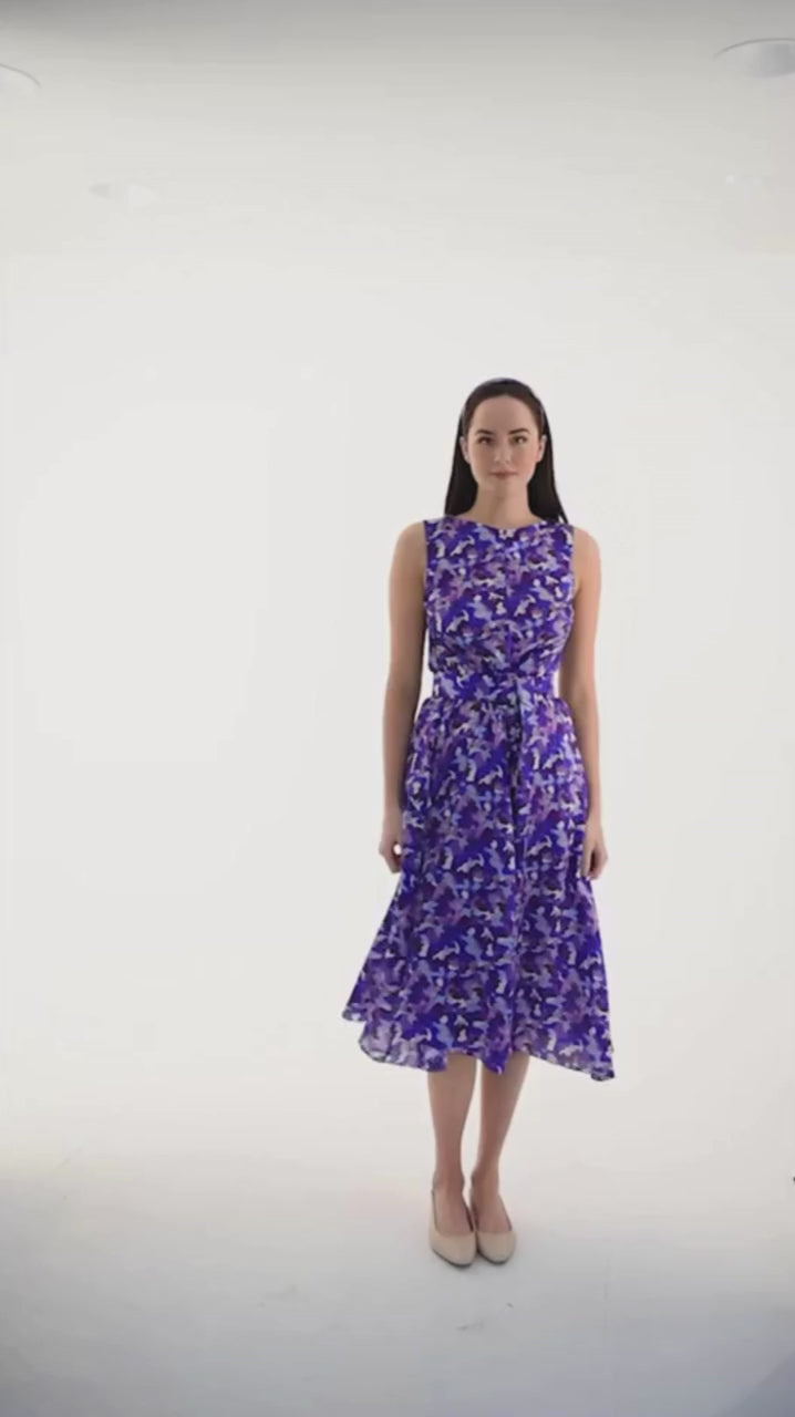a video showing a women wearing a purple printed silk cotton sleeveless dress walking to the camera styled with a matching fabric belt