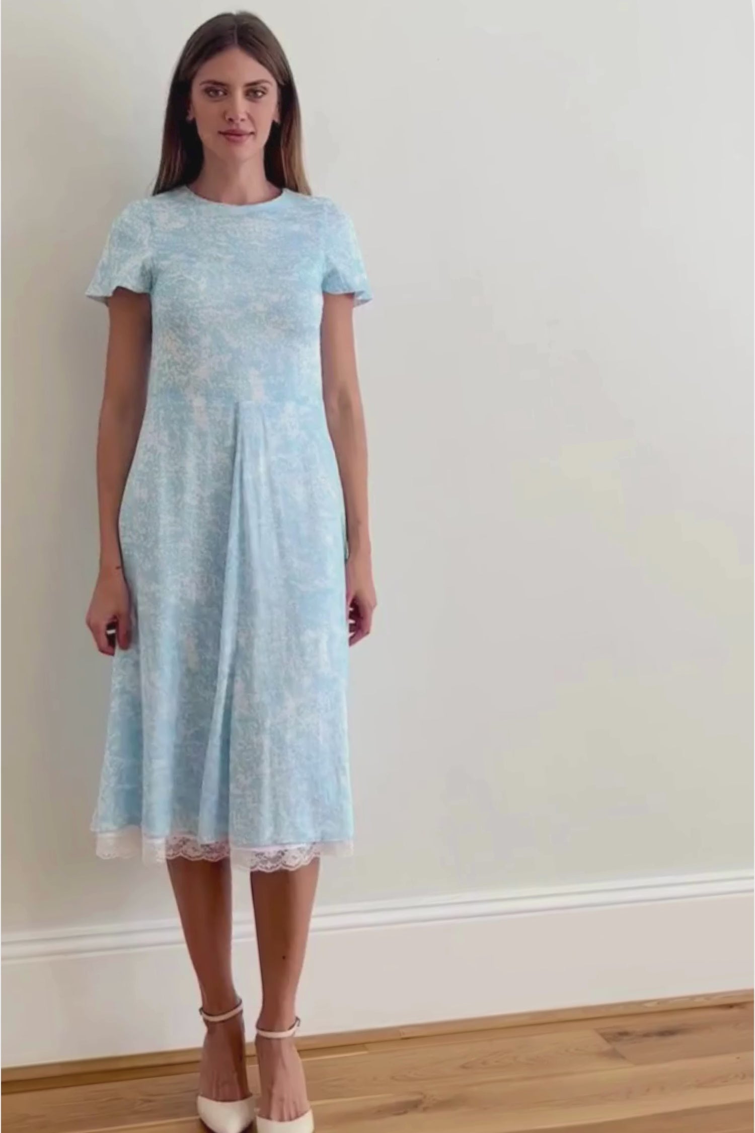 a model walking in a video to show the stunning midi dress with white lace trim detail at the hem