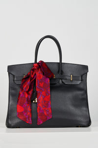 a skinny scarf accessorised as a bow on a handle of a birkin bag for extra detail and colour