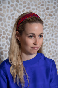 a red printed headband inspired by pebbles handmade in London worn by a model to give a bit of colour