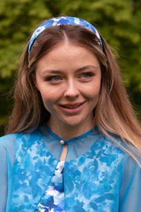 A silk satin blue petal printed headband worn by a model to match her outfit