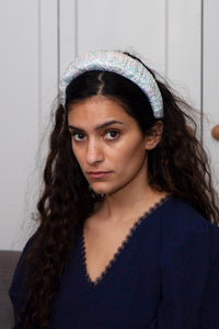 A subtle printed beige and pink mosaic padded headband worn by a model