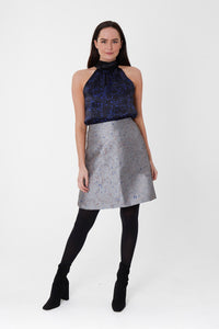 a silver short skirt paired with a silk top and black boots.