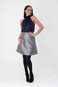 silver jacquard short skirt worn by a model paired with black boots and a navy and black silk halter neck top