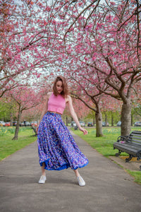Model wearing reversible voluminous a-line midi silk satin vibrant cobalt skirt, worn with pink racerback cropped vest.