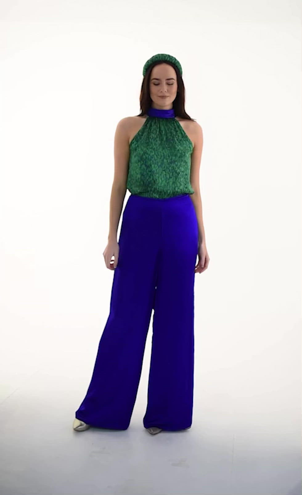 A video of a model wearing reversible halter neck silk satin top with tie collar in vibrant green print with matching Phoebe Palazzo Pants cobalt.